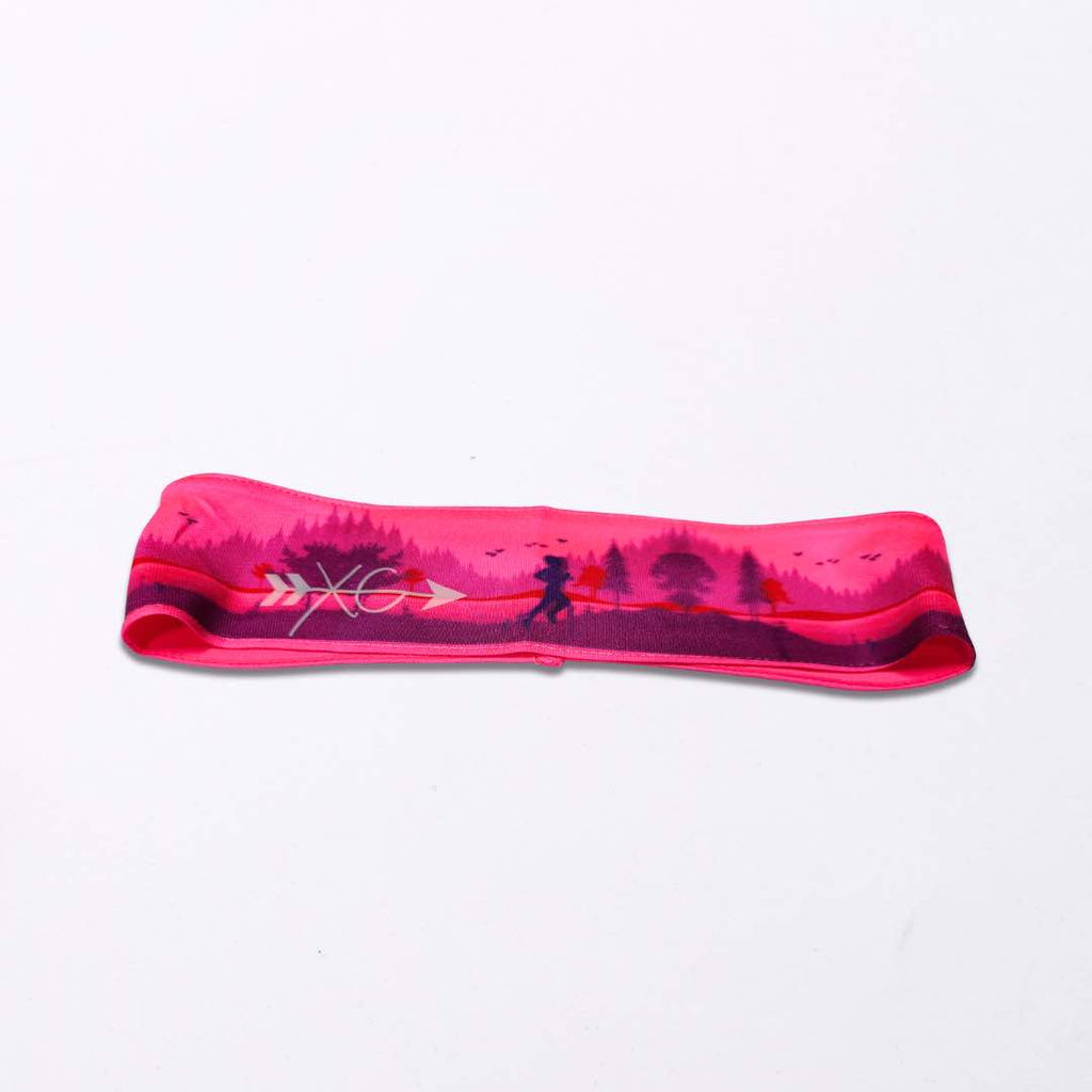 A close-up image of the Runner on a Trail Headband made from polyester fabric with a silicone grip for a secure fit. It’s a one size fit all headband and it’s available in two shades of pink.