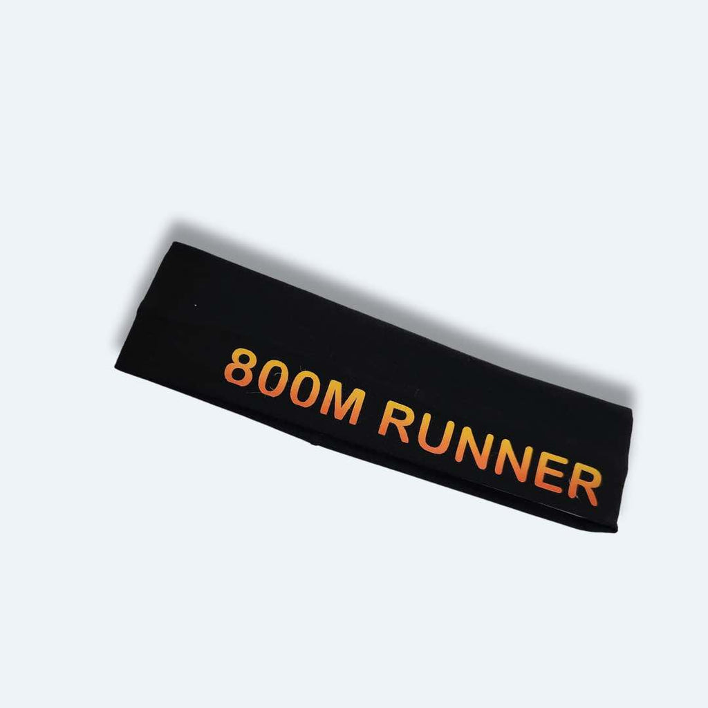 The ‘800 Metres Training Headband’ has the words "800M Runner" printed on it. This headband is made of 100% cotton fabric with silicone for a firm hold, making it perfect for intense workouts. It comes in Black and Light Grey