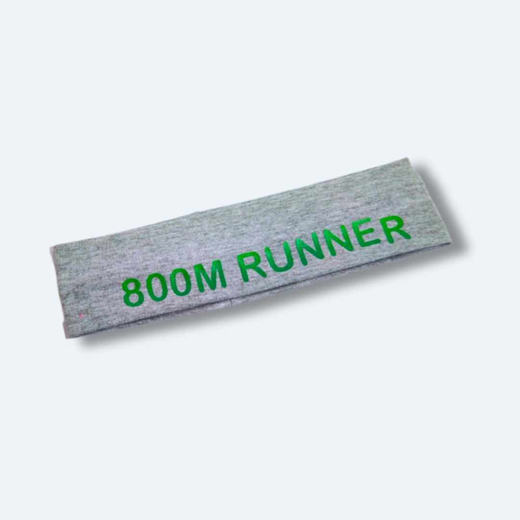 The ‘800 Metres Training Headband’ has the words "800M Runner" printed on it. This headband is made of 100% cotton fabric with silicone for a firm hold, making it perfect for intense workouts. It comes in Black and Light Grey