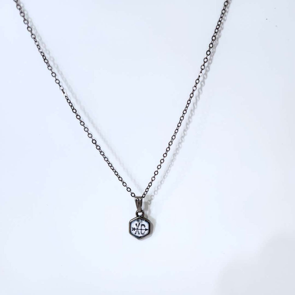 This gunmetal black necklace is handmade. It has the letters ‘XC’ with arrow across it in the clear resin dome. The stainless-steel frame and chain makes it lightweight, comfortable, and durable. The ideal gift for cross country athletes and enthusiast.