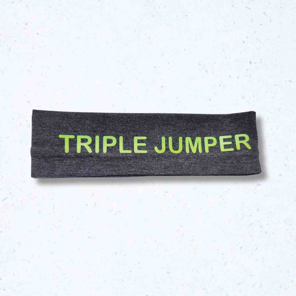 This dark grey 'Triple Jumper Headband' with green 'TRIPLE JUMPER' lettering print on it, demonstrates both style and practicality for athletes. With a silicone hold, this headband stays beautifully in place.