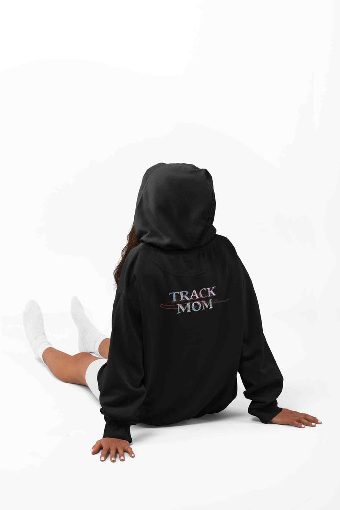 An image of a lady wearing a black hoodie with a bold colorful print of 'TRACK MOM' stylishly placed across the back.  The ideal gift for the track mom who love to crush the morning run or cheer from the sidelines.