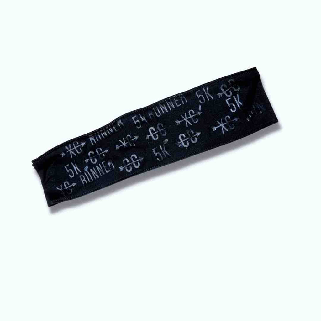 A black headband with the words ‘5k’, ‘Runner’, ‘CC’, and ‘XC’ written on it in light grey. The headband is made of a soft, and stretchy material suitable for long distance and cross-country races. Also available in Black, White, Pink and Charcoal Grey.