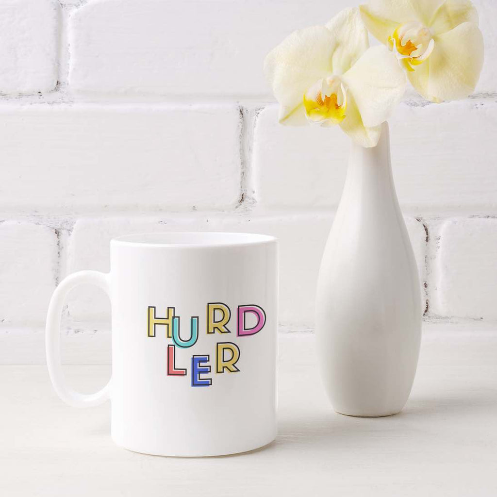 A white ceramic coffee mug with a colorful print of the word 'HURDLER' on it.  Crafted from durable ceramic for hurdlers and sport enthusiasts. It is microwave and dishwasher friendly.  