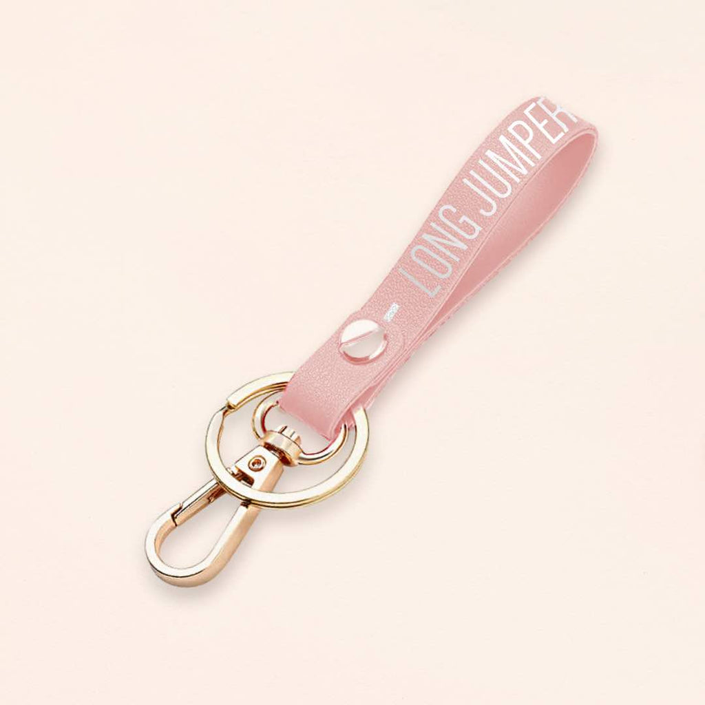 Athletic Accessory A close-up photo of a pink leather keychain with intricate lettering of a Long Jumper with a metal finish