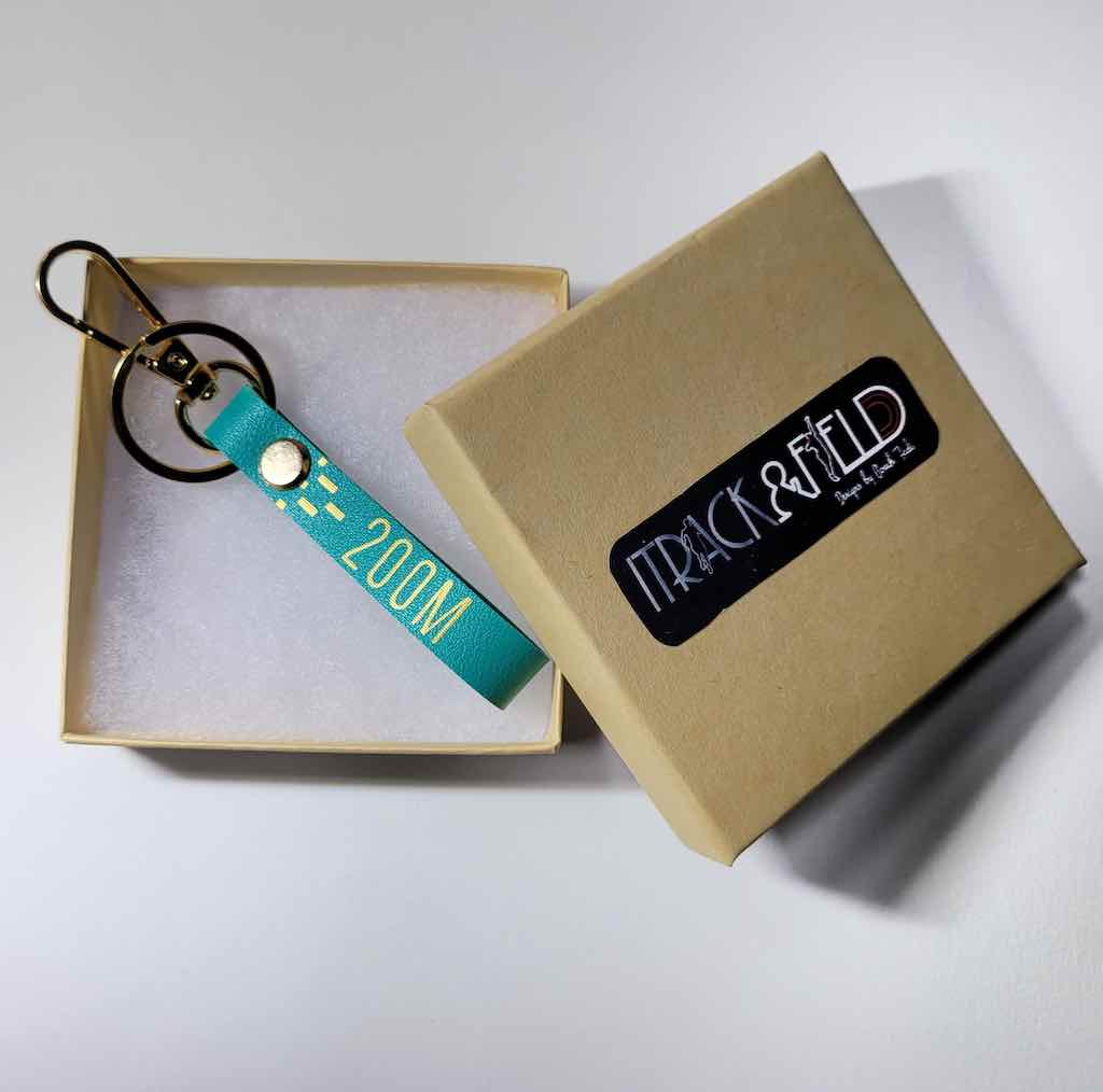 A close-up photo of a Teal leather keychain with intricate details of a 200m sprinter lettering, perfect for keeping keys organized and showing off athletic style.